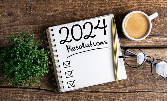Journal for 2024 resolutions on wood with coffee and glasses
