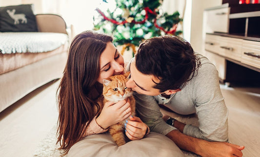 White couple on living room floor hugging cat