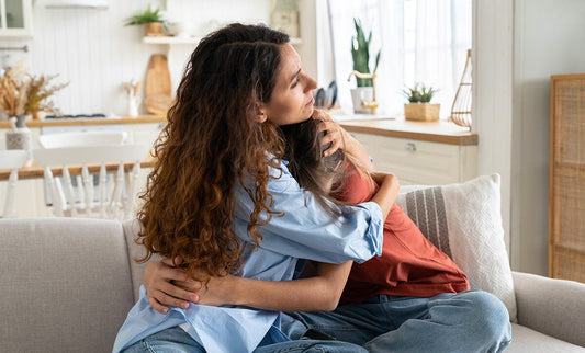 Mom hugging daughter on sofa