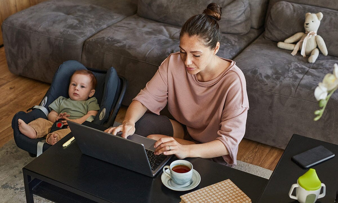 Mom with baby working on computer on living room floor